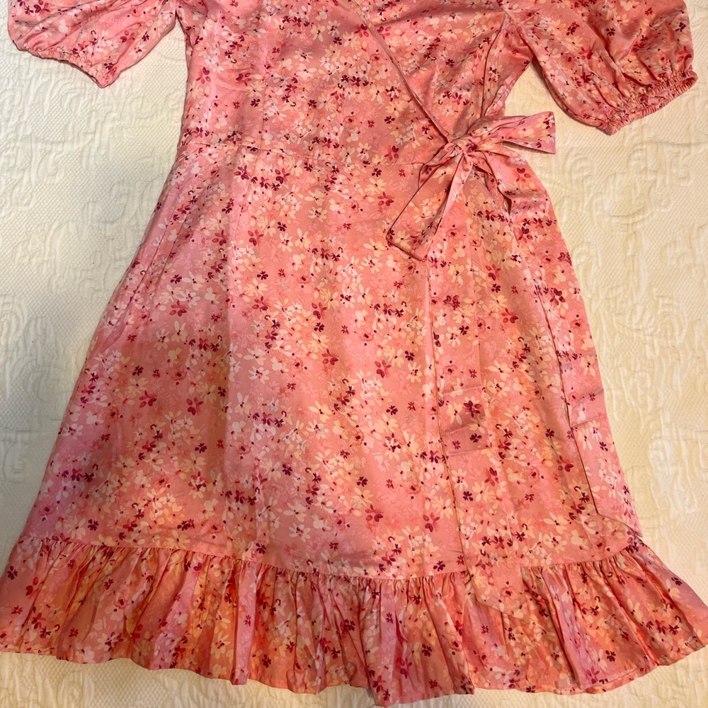 Women’s pink ditsy floral dress with faux wrap style, and small ruffle hem.
